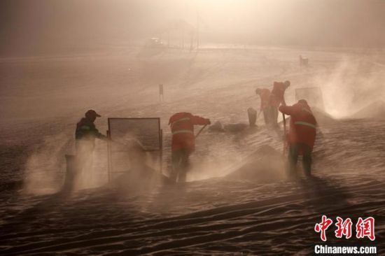 圖為敦煌市鳴沙山月牙泉景區(qū)“駱駝保姆”清理駱駝糞便?！垥粤?攝