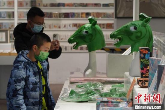 圖為“神馬來了”銅奔馬頭套吸引參觀者駐足?！【琶赖┰?攝