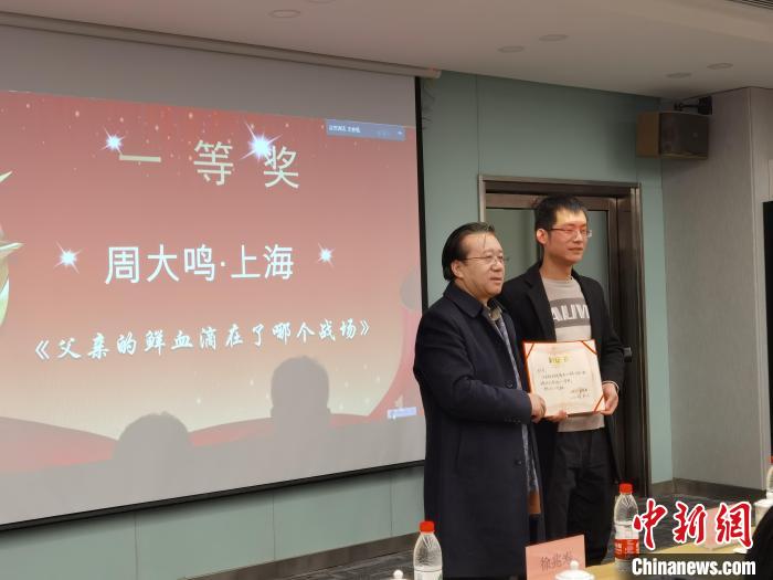 圖為作家、西北師范大學(xué)新聞與傳媒學(xué)院院長(zhǎng)徐兆壽頒發(fā)一等獎(jiǎng)證書，代領(lǐng)獎(jiǎng)?wù)呱吓_(tái)領(lǐng)獎(jiǎng)?！钅?攝