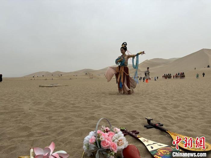 圖為2023年4月底，敦煌大漠“逐舞者”奧楠在鳴沙山月牙泉景區(qū)視頻直播敦煌舞?！●T志軍 攝