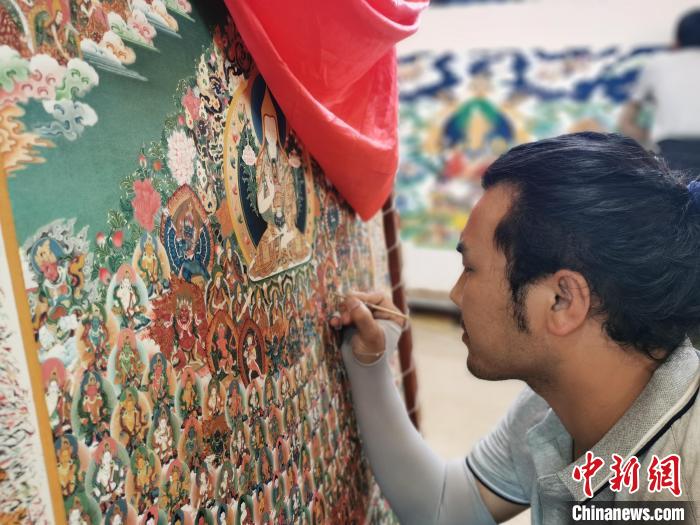 圖為更登才讓的徒弟繪畫唐卡?！?zhí)砀?攝